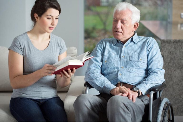 Caregiver reading to client in wheelchair