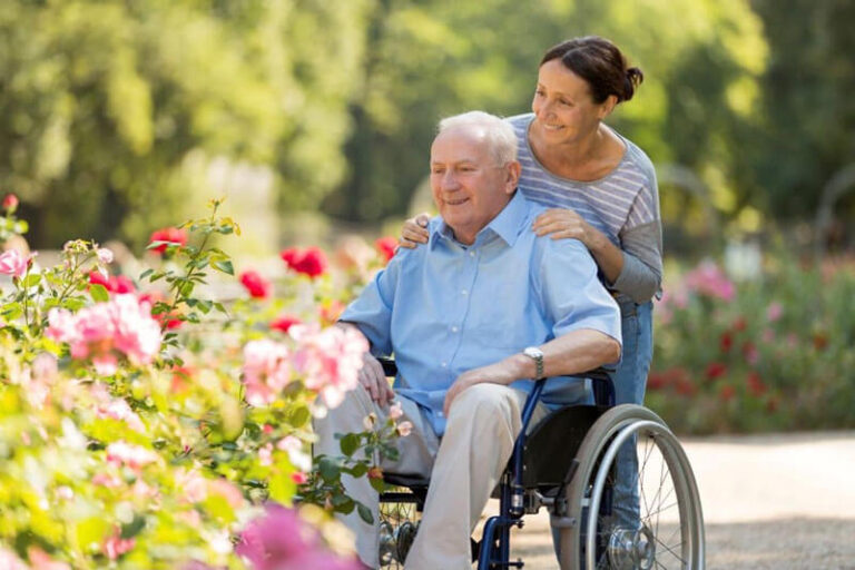 Caregiver with senior client in wheelchair looking at flowers